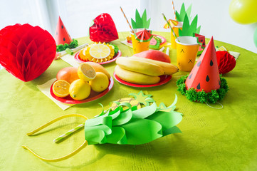 Decor for a holiday of children's birthday. Fruit party. Cake and sweet candy. Disposable tableware and tropical fruits.