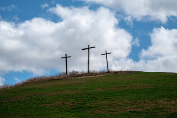 3 Wooden Crosses On hillside With Blue Cloudy skies In Remembrance of Religious Easter holiday 