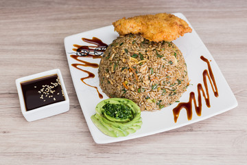 Torimeshi with fried fish, soy sauce and avocado on a wooden table