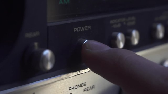 Switching on/off old retro amplifier, with wooden edges and aluminium knobs.
