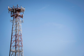 A metal cellular communications tower set on a clear blue sky background.