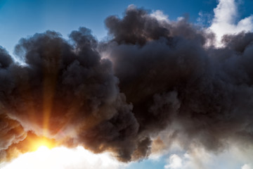 Thick black acrid smoke on the sky background
