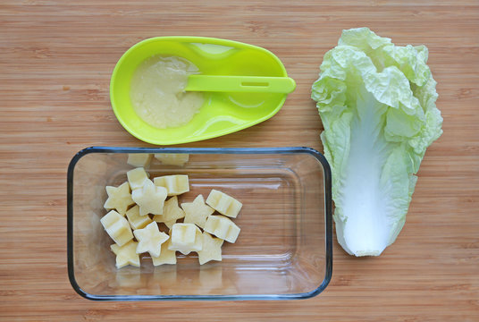 Frozen baby food homemade, yellow star from lettuce Cubes in square glass bowl on wooden board.