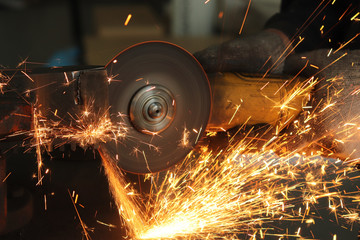 worker, grinder cuts metal and from this a huge amount of sparks
