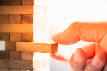 ..Businessman holding wooden block toy with city and clear ans sun light backgrounds. Business strategy, learning and development concepts.