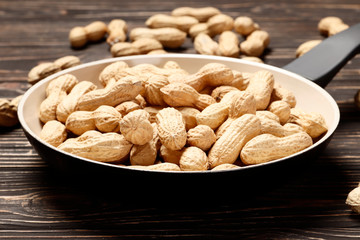 Roasted peanuts in a pan on a wooden background. Place for text.