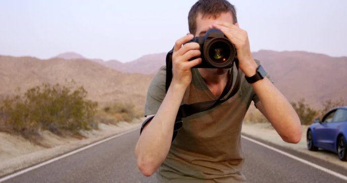 Trendy young photographer taking photos on desert highway - close up