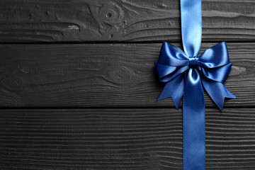 Beautiful gift blue bow and ribbon on a black wooden background. Congratulations concept.