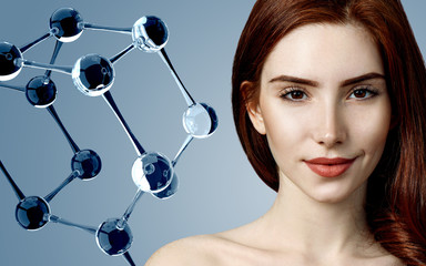 Beautiful redehead woman near big white molecule structure.