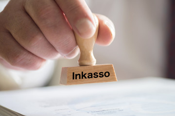 Ein Mann und Stempel mit dem Aufdruck Inkasso