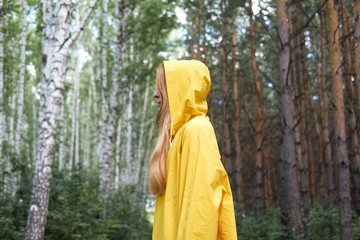 Fototapeta na wymiar A woman in a yellow raincoat in the woods.