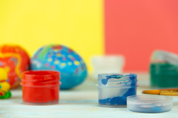 Close-up paints and brush on multicolor wooden background with Easter eggs Easter crufts