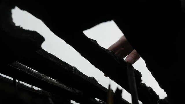silhouette hand of young man breaking a burnt pallet on field after a fire.Slowmotion