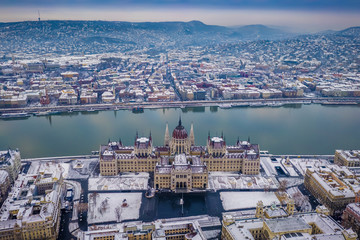 Budapest, Hungary - Aerial view of the snowy Parliament of Hungary at winter time with River Danube...