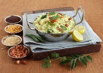 Lemon rice, a traditional, popular, and homemade south Indian vegetarian breakfast in a wok, and its main ingredients.