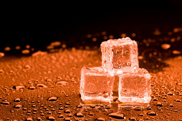 Water drop with ice cubes on lighting red background.