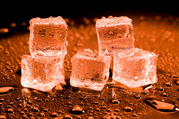 Water drop with ice cubes on lighting red background.