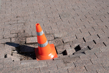 Traffic cone on a damaged sidewalk