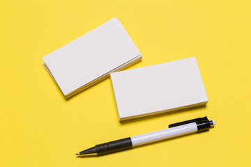 Blank white business cards on yellow background. Mockup for branding identity.