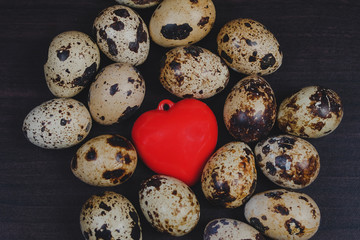 Fresh Quail eggs with red heart on background.Food and health concept.