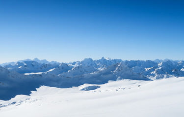 Fototapeta na wymiar Snowy peaks of Caucasian Mountains in the blue sky. Elbrus region