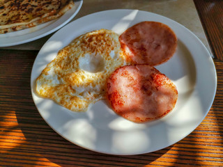 Scrambled eggs from one egg with ham on a white porcelain plate.