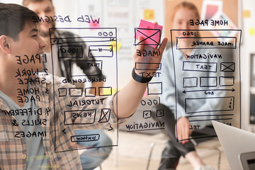IT designers discussing project, view through transparent board