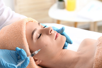 Fototapeta premium Young woman receiving filler injection in beauty salon