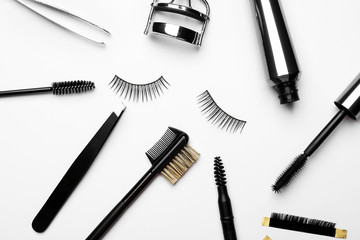 Mascara with false eyelashes and tools on white background