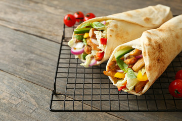 Cooling rack with tasty doner kebab on wooden table