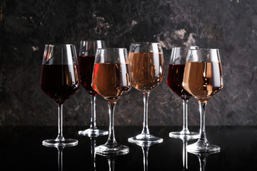 Glasses of different sorts of wine on dark table