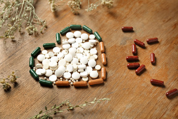 Obraz na płótnie Canvas Heart made of plant based pills on wooden background