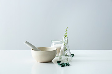 Composition with mortar, flask and plant based pills on table