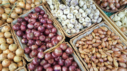 mix of bulb onion in sale baskets on market counter
