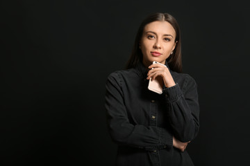 Stylish businesswoman with mobile phone on dark background