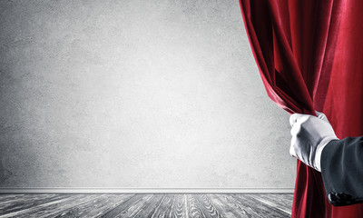 Concrete wall behind drapery curtain and hand opening it