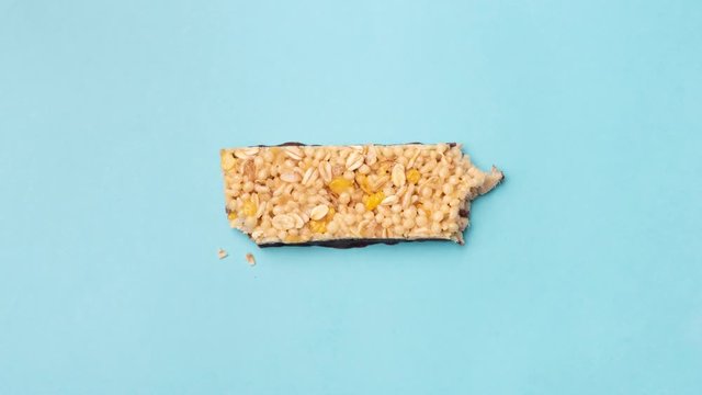 Granola Protein bar on blue background stop motion animation. Eating granola bar. Top view. 4K Footage