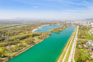 Fototapeta na wymiar Zagreb, Croatia, Jarun lake, beautiful green recreation park area, sunny spring day, panoramic view from drone, city in background