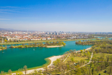 Zagreb, Croatia, Jarun lake, beautiful green recreation park area, sunny spring day, panoramic view from drone, city in background