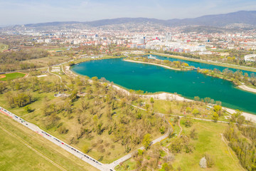 Zagreb, Croatia, Jarun lake, beautiful green recreation park area, sunny spring day, panoramic view from drone, city in background