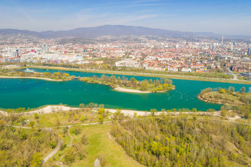 Fototapeta na wymiar Zagreb, Croatia, Jarun lake, beautiful green recreation park area, sunny spring day, panoramic view from drone, city in background