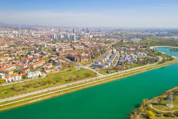 Fototapeta premium Zagreb, Croatia, Jarun lake, beautiful green recreation park area, sunny spring day, panoramic view from drone, city in background