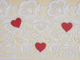 White lace on a beige background with red hearts