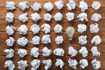 Ideological concept with wastepaper light bulb on wooden table
