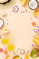 Colorful summer concept flat lay with fresh juice, tropical fruits, lollipops and multicolor seashells, copyspace