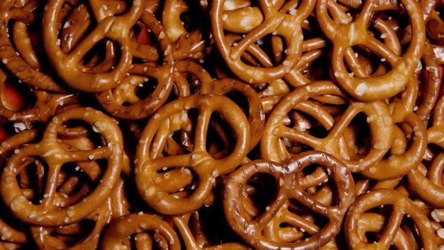 Many salted pretzel snacks on a rotating surface. Above medium close-up shot.