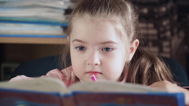 Smart beautiful girl rewrites alphabet from book to notebook in school of early development