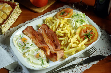 Una bandeja con, dos huevos fritos, bacon, ensalada y patatas fritas.