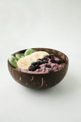 Healthy smoothie with fruits, plate made from coconut shell and wood spoon