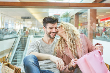 Junge Frau küsst ihren Freund beim Shopping